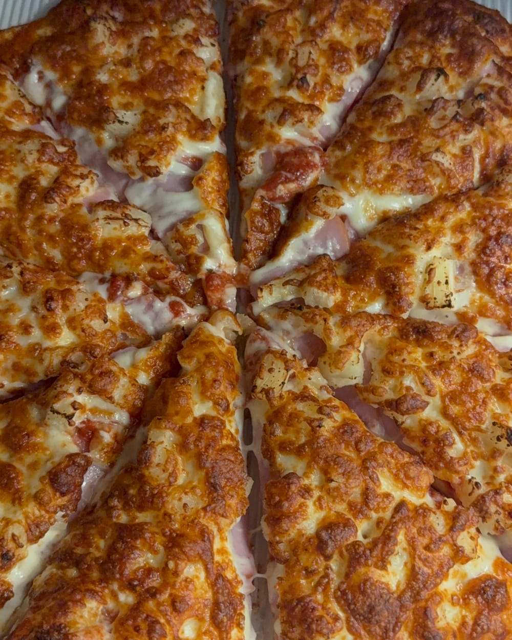 Slices of ham and cheese pizza, cut and ready