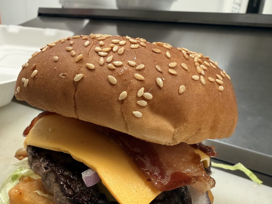A cheeseburger with bacon and lettuce on a sesame bun
