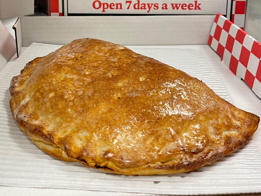 A golden calzone in a Captain Pizza box